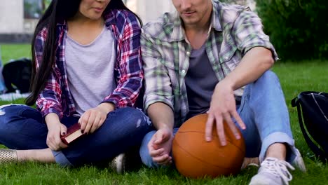 Male-and-female-students-sitting-on-lawn-closely,-having-conversation,-flirting