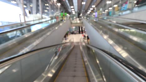 Desenfoque-la-vista-de-movimiento-de-personas-en-escaleras-mecánicas-en-la-puerta-del-aeropuerto,-movimiento-de-pie-en-la-acera.-Imágenes-Defocused