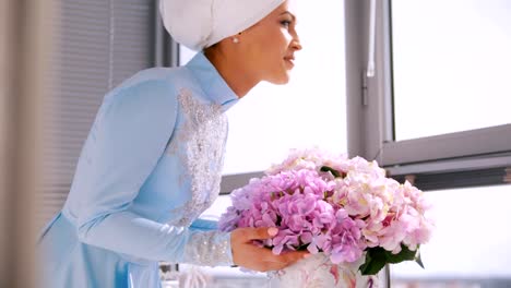 Muslim-bride-in-blue-wedding-dress-for-nikah,-smelling-flowers