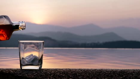 Male-hand-pouring-whiskey-into-glass-and-airplane-flying-in-evening-sky