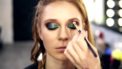 Make-up-stylist-finished-green-smokey-eyes-make-up-for-fair-hair-model.-She-slowly-open-her-eyes.-Front-view.-Slow-motion