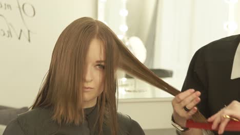 Haircutter-combing-and-cutting-woman-hair-with-hairdressing-scissors-in-beauty-studio.-Close-up-hairstylist-making-female-haircut-with-scissors-in-hairdressing-salon