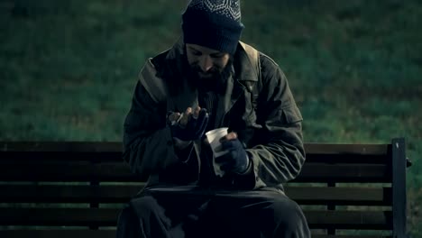 Lonely-homeless-in-the-park-at-night,counting-his-money-to-buy-something-to-eat