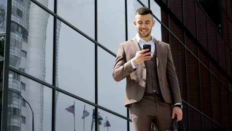 Geschäftsmann-mit-seinem-Smartphone.-Hübscher-junger-Mann-kommunizieren-auf-Smartphone-lächelt-zuversichtlich