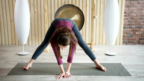 Schöne-sportliche-sportliche-Frau-Yoga-Übungen-drinnen.-Stretching-Übung-in-der-Turnhalle