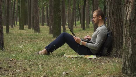 Joven-está-trabajando-en-la-laptop-en-el-bosque