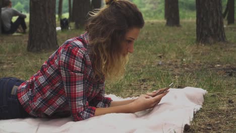 Curly-woman-is-laying-at-the-blanket-in-the-park