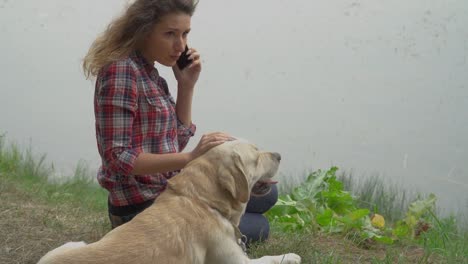 Perro-y-mujer-pelirroja-está-descansando-cerca-del-agua-juntos