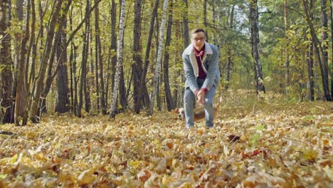 Man-with-a-dog-running-through-autumn-forest