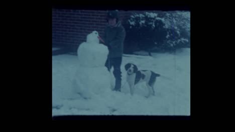 1963-kleiner-Junge-mit-seinem-Hund-spielen-im-Schnee-bauen-Schneemann