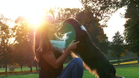 Liebevolle-weibliche-Tierbesitzer-streicheln-und-umarmen-glücklichen-Hund-am-Nachmittag-Spaziergang-in-einem-Park.