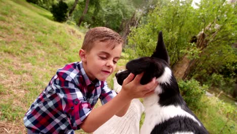 Little-boy-hugging-and-stroking-his-puppy-dog-in-park