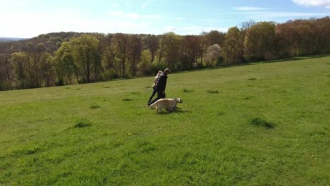 Toma-aérea-de-pareja-y-perro-en-a-pie-de-campo