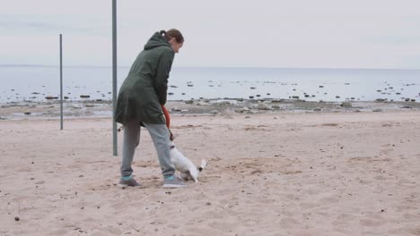 Frau-spielt-mit-Hund-am-Ufer-Meeres