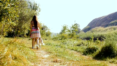 Una-joven-se-hace-caminando-con-un-husky-en-el-bosque.