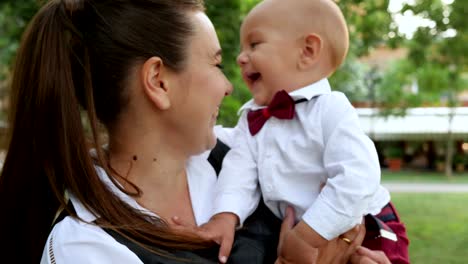 Familie,-close-up-niedlichen-jungen-im-Anzug-auf-den-Händen-der-Mutter-Natur-im-freien