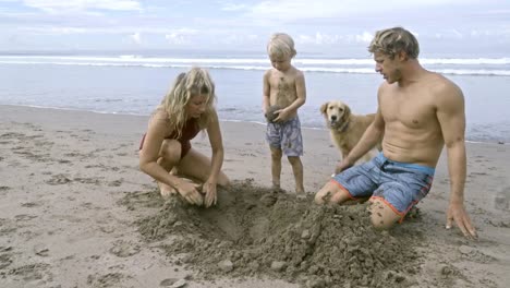 Parents-Digging-in-Sand-with-Kid-and-Dog-at-Beach