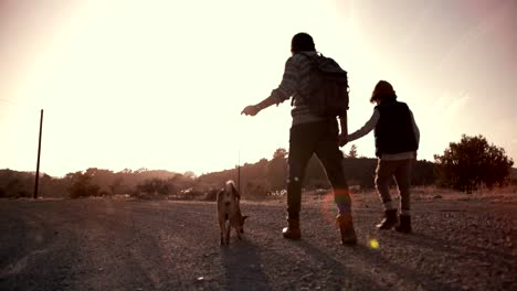 Young-father-and-son-walking-on-mountain-footpath-with-dog