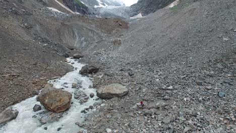 Woman-traveler-with-a-dog-walks-along-a-mountain-gorge-to-the-glacier.