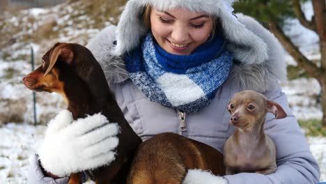 Mujer-jugando-con-sus-pequeños-perros-fuera-de-invierno