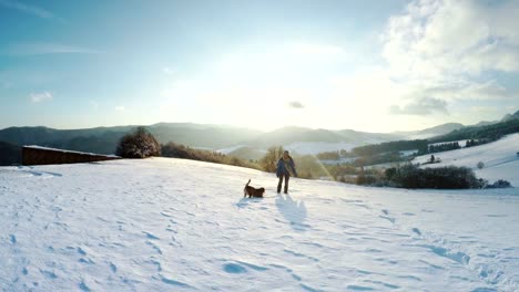 Frau-zu-Fuß-durch-den-Schnee-und-ihr-Hund-läuft-vor