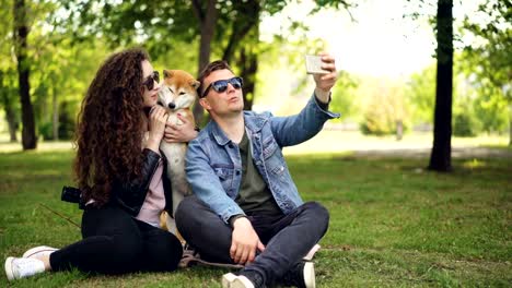 Populäre-Blogger-ist-die-Videoaufnahme-über-sich,-seine-Frau-und-niedlichen-Hund,-Mann-hält-Smartphone,-reden-und-schauen-in-die-Kamera-dann-auf-die-Frau-und-das-Tier.