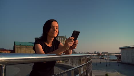 cheerful-woman-typing-a-message-on-the-sunset