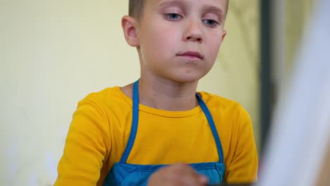 Handsome-boy-with-different-paints-on-face-painting-on-easel