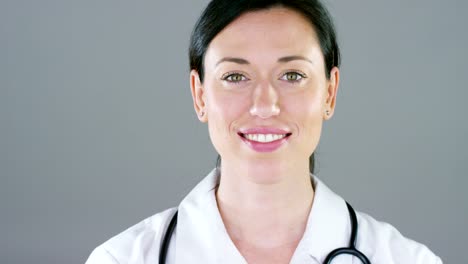 Portrait-of-a-female-doctor-with-white-coat-and-stethoscope-smiling-looking-into-camera-on-white-background.