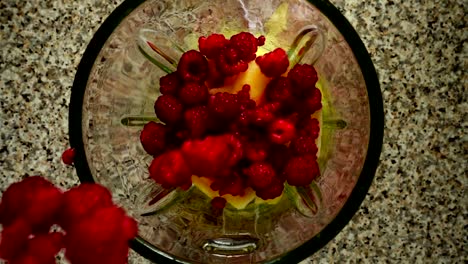 Raspberry-falls-in-a-blender-bowl-on-pieces-of-apples.-Slow-motion.	Shooting-in-kitchen.-Top-view.