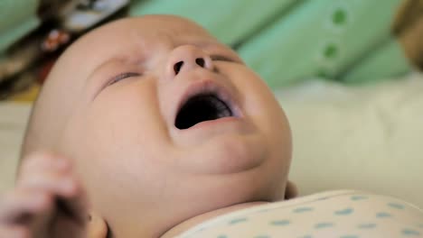 Close-up-of-a-newborn-boy-crying-lying-in-his-crib,-in-slow-motion.