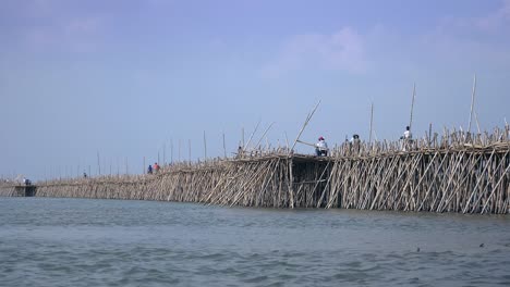 Atasco-de-tráfico-en-el-puente-de-bambú-sobre-el-río-Mekong;-motos-y-bicicletas-que-(vista-posterior)