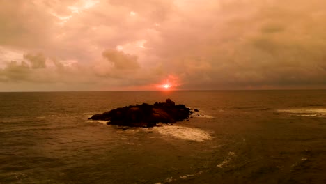 Der-Flug-über-die-kleine-Insel-im-Ozean-auf-dem-Sonnenuntergang-Hintergrund