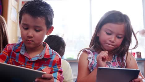 Tres-alumnos-utilizando-tabletas-durante-la-lección-en-la-escuela