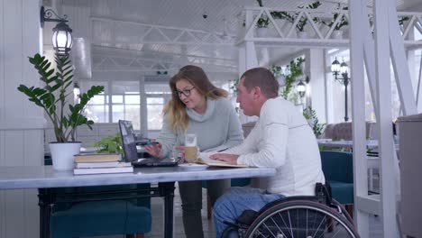 successful-disabled,-creative-freelance-businessman-in-wheelchair-With-woman-discuss-startup-business-using-laptop-computer