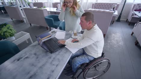 home-education,-successful-disabled-man-in-wheelchair-with-teacher-female-using-modern-computer-technology-during-individual-training