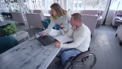 Hombre-inteligente-estudiante-inválido-en-silla-de-ruedas-con-las-mujeres-de-tutor-durante-la-educación-personal-utilizando-la-tecnología-de-la-computadora-moderna