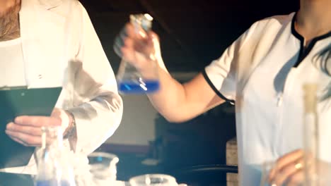 two-doctors-in-eyglasses-are-experimenting-with-test-tubes-with-chemicals-at-a-table-in-the-laboratory-on-a-black-background.