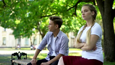 Offended-teen-couple-sitting-in-park-on-bench,-ignoring-each-other,-conflict