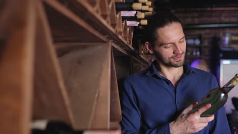 Hombre-guapo-con-botella-de-vino-en-la-bodega