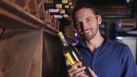 Handsome-Man-Holding-Bottle-Of-Wine-At-Wine-Cellar