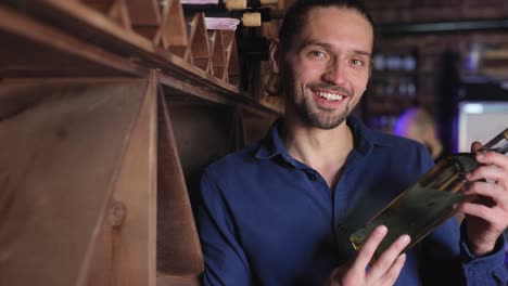 Hombre-guapo-con-botella-de-vino-en-la-bodega