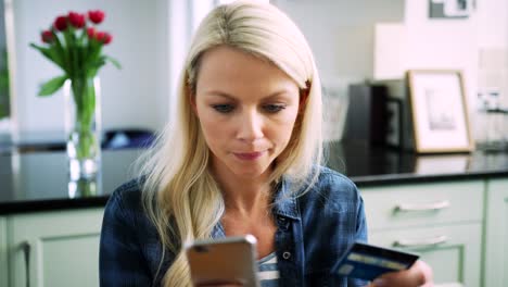 Hermosa-mujer-rubia,-escribir-los-datos-de-tarjeta-de-crédito-en-teléfonos-inteligentes