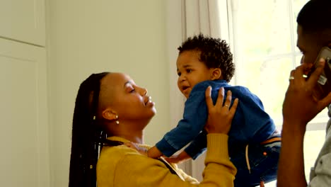 Side-view-of-young-black-mother-playing-with-her-baby-in-a-comfortable-home-4k