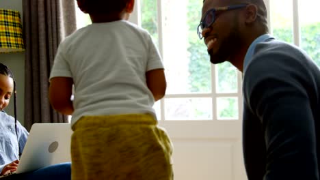 Side-view-of-young-black-father-playing-with-his-son-in-living-of-comfortable-home-4k