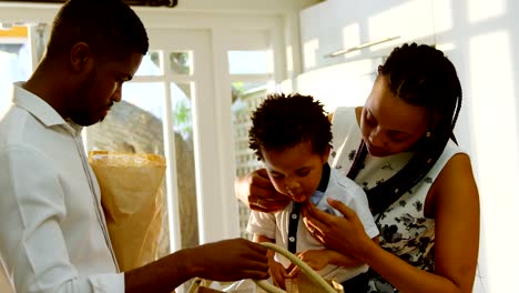 Front-view-of-young-black-mother-and-son-looking-in-grocery-bag-in-kitchen-of-comfortable-home-4k