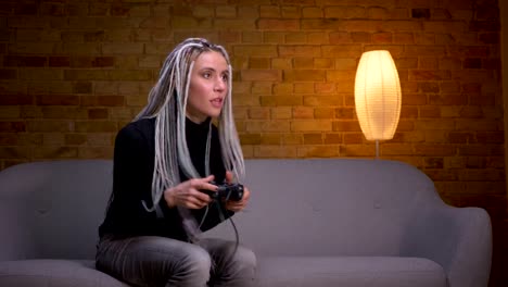 Closeup-shoot-of-young-attractive-caucasian-hipster-female-playing-video-games-on-TV-and-failing-a-level-sitting-on-the-couch-indoors-in-a-cozy-apartment