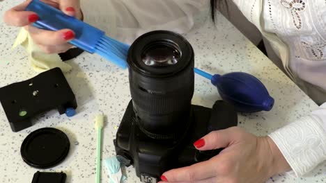 Woman-photographer-maintenance-a-DSLR-Camera-with-brush-in-her-hand