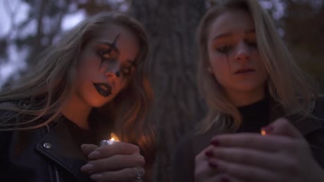 Two-caucasian-blonde-women-with-Halloween-makeup-holding-small-candles-in-hands-and-looking-at-the-camera.