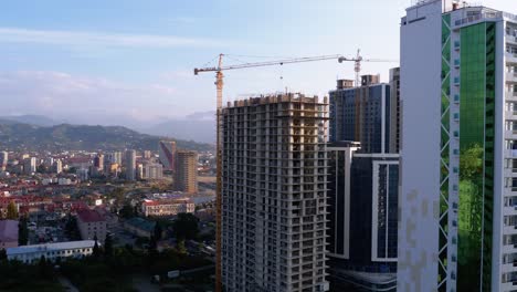 Construcción-de-edificios.-Una-grúa-en-un-sitio-de-construcción-levanta-una-carga.-Trabajadores-en-una-obra-de-construcción